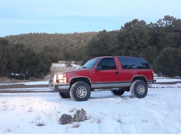 Red lifted 4x4 SUV parked in a snowy landscape